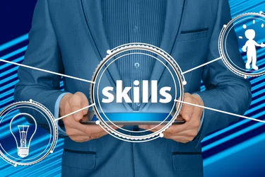 Skills: Mann im blauen Anzug hält Tablet mit Symbolen für Ideen und Erfolg.